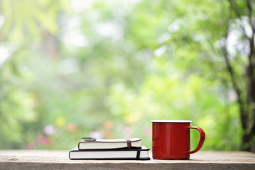 Red mug and notebooks on wooden table