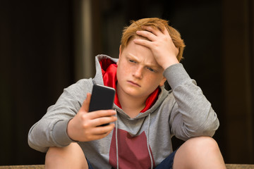 Sad Boy Looking At Mobile Phone