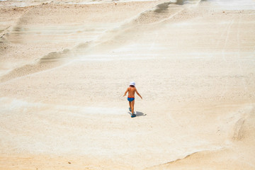 Little boy walking on the beautiful Sarakiniko beach on Milos island, Greece.