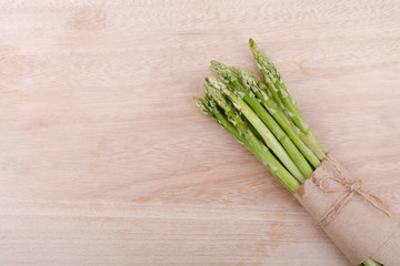 uncooked green asparagus tied with twine from above on wooden
