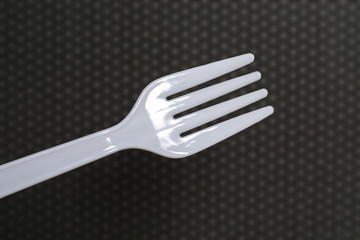 White plastic fork on blurred pattern background.