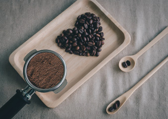 heart from coffee beans and wooden spoons with coffee maker prepared on the desktop