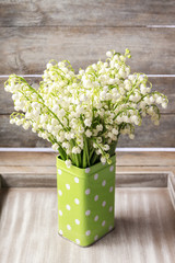 Bouquet of lily of the valley flowers in dotted green can.