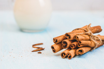 Pitcher glass of milk with cinnamon and cocktail tube on blue wooden background