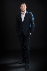 Portrait of handsome stylish man in elegant suit on black background