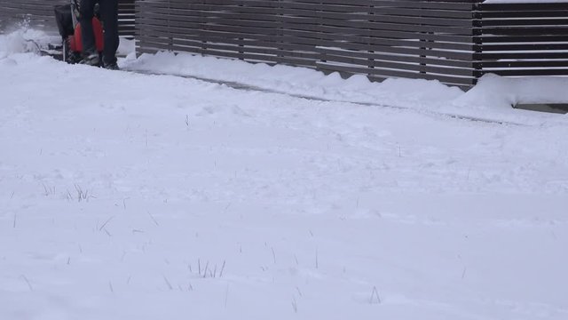 Man working with snow blowing machine on pavement after snow fall in winter. 4K