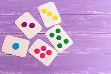 Kids colored flash cards on lilac wooden background with copy space for text. Handmade cardboard cards to teach children color, shape and quantity. Early development in kindergarten, at home