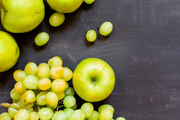 Grapes and apples on a black wooden background, horizontal, soft focus