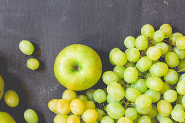 Grapes and apples on a black wooden background, horizontal, soft focus