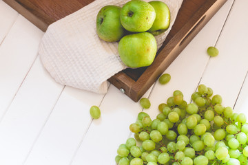 Bunch of grapes with apples on wooden tray, white background, toned, soft focus