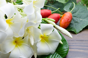 Obraz na płótnie Canvas A group of white plumeria flower and red gourd on wooden backgro
