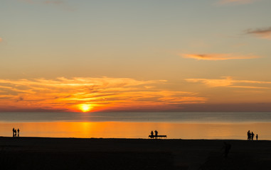 Sunset and silhouettes of walking tourists at sandy beach in Jurmala - famous international Baltic resort, Latvia, Europe