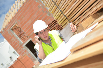 Foreman using walkie-talkie and digital tablet on construction site