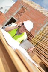 Foreman using walkie-talkie and digital tablet on construction site