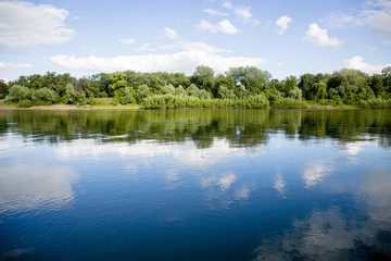 Lake with reflection of clouds and forests, serenity