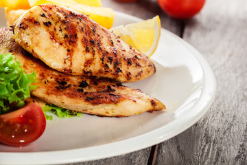 Grilled chicken breasts served with fries and fresh salad
