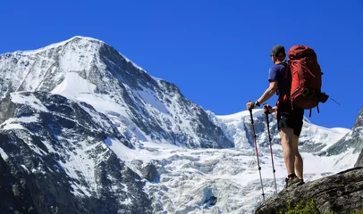 Fotobehang Hiker with backpack looking at mountain Pigne d' Arolla in Wallis, Switzerland, on a summers day. © sanderstock