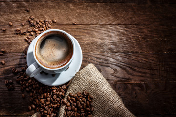 white mug of coffee beans on a wooden background