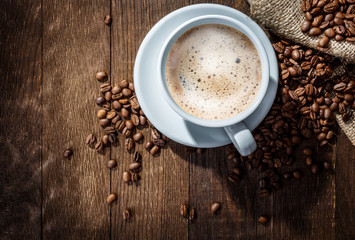 white mug of coffee beans on a wooden background