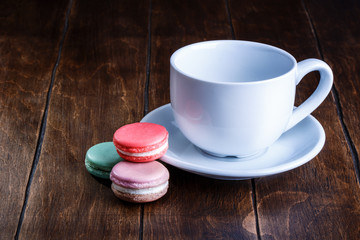 Fototapeta na wymiar macaroon and white cup of coffee on a wooden background