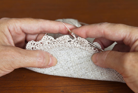 Needlework. Female hands crochet linen doily