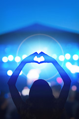 Girl making a heart-shape symbol for her favorite band.