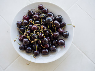Red tasty cherries on a white plate.