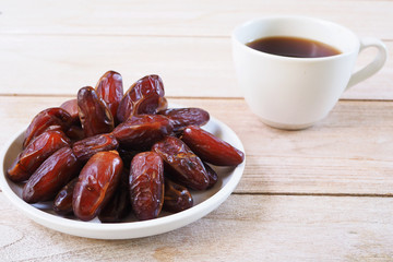 Top view of pile of dried date fruit with black coffee  on a wooden table.