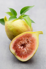Whole figs and one fig sliced in half on top of a gray table.