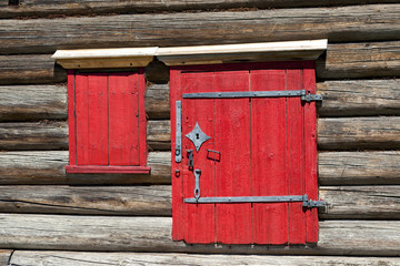 Red old door and window on the wooden wall of a village house. Excellent background.