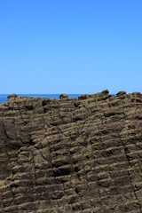 塩俵岩 ／ 山形県温海海岸の奇観、塩俵岩（しおたわらいわ）を撮影した写真です。この俵を積んだような奇岩、塩俵岩は玄武岩脈の一塊で、よく発達した層状節理と、これに直角に発達した五角形または六角形の柱状節理とが、交互に交差してあたかも塩俵を積み重ねたような奇観を呈するので、この名が付いたと伝えられています。 - obrazy, fototapety, plakaty