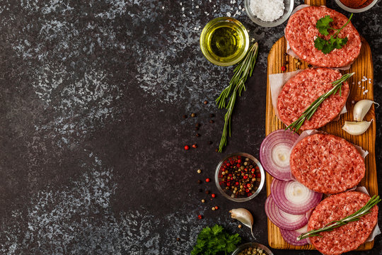 Raw ground beef meat steak cutlets with herbs and spices.