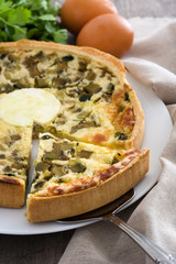 French quiche with vegetables on a rustic wooden table

