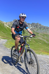 Fototapeta premium gutgelaunter Mountainbiker im Gebirge im Anstieg