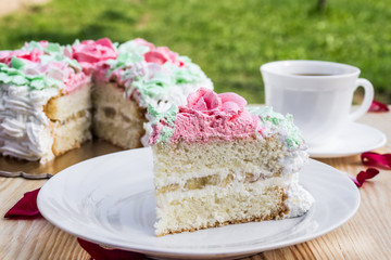 Piece of sponge cake  with curd cream  and banana on  background of cake and cup of coffee