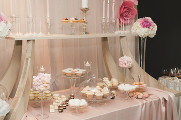 Delicious and tasty dessert table with cupcakes shots at reception closeup