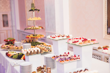 Delicious and tasty dessert table with cupcakes shots at reception closeup