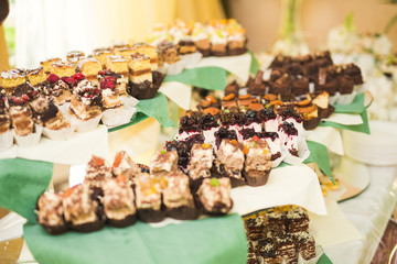 Delicious and tasty dessert table with cupcakes shots at reception closeup