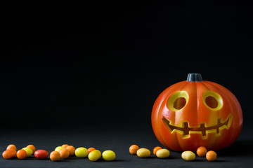 Halloween pumpkin and candies on black background

