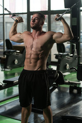 Fototapeta na wymiar Young Bodybuilder Doing Exercise For Biceps On Machine