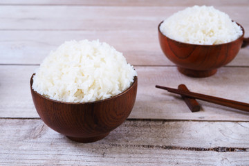 Close up of a bowl of cooked jasmine rice on a wooden table. 