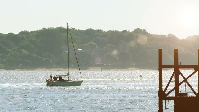 Small sailing vessel leaving harbor at dawn in the summer