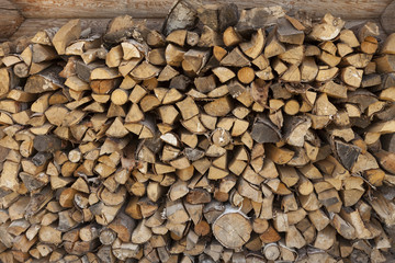 A pile of firewood at the wall of the wooden house