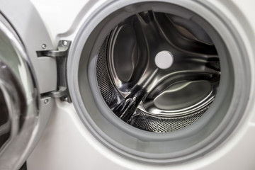Opened door of empty washing machine with a drum and a horizontal load of laundry