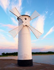White windmill by sea on rocky coast. Seascape and landscape