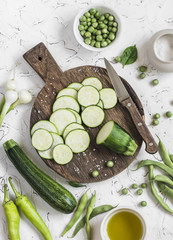 Cut zucchini on rustic cutting board, peppers, green beans on a white background. Raw ingredients. Cooking background