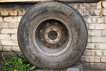 Old used car wheel stands near wall