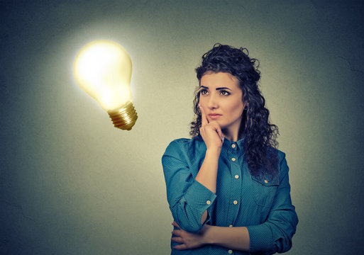Woman thinking dreaming looking up at bright light bulb