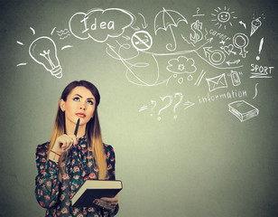 young woman with book and pen thinking dreaming looking up