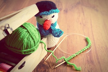 knitting with green wool on wooden table